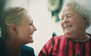 Yngre og ældre kvinde smiler til hinanden.