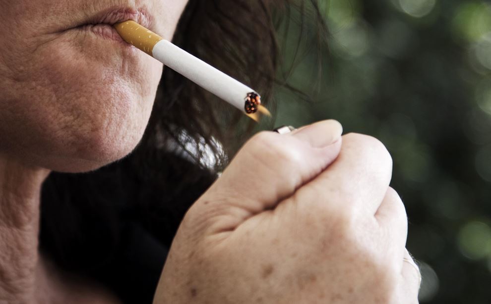 En mørkhåret kvinde er i gang med at tænde en cigaret