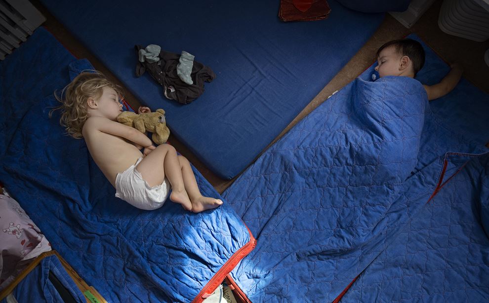To børn ligger og sover på madrasser