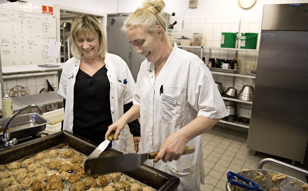 Køkkenmedarbejder Britta Larsen steger frikadeller, og serviceleder Helle Conradsen ser på.