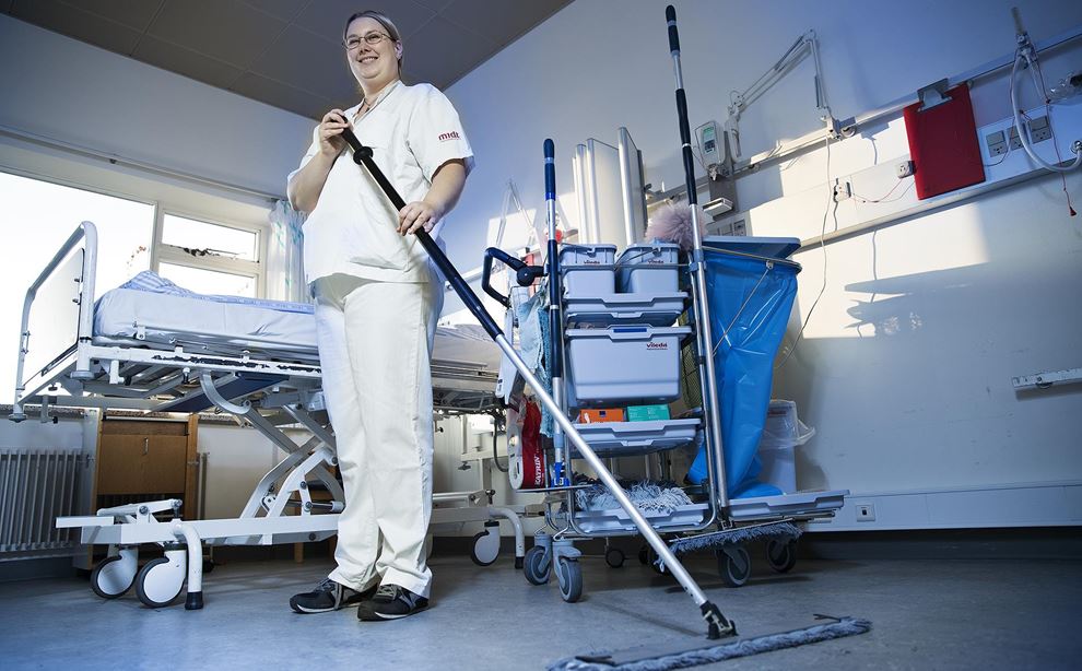 Kvinde i hvid kittel gør rent på hospitalsstue