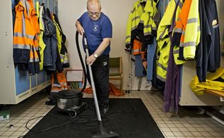 Rengøringsmedarbejder Pauls Shanks i gang med at støvsuge