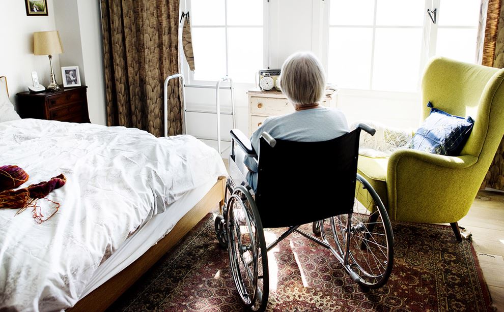 Ældre kvinde i kørestol på plejehjem