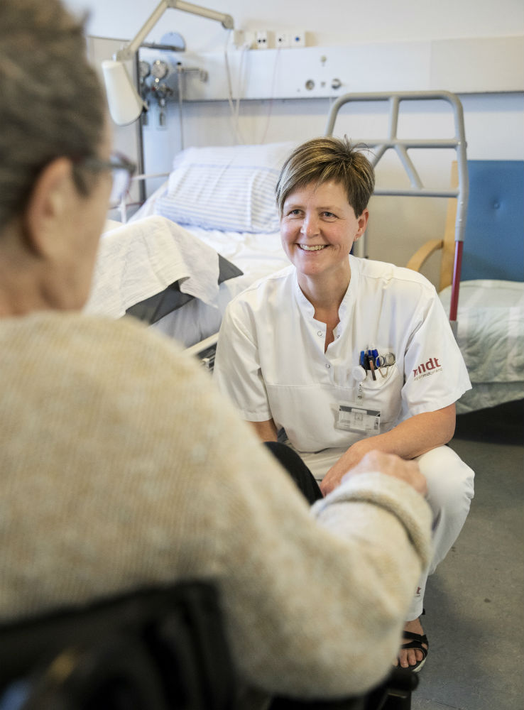 Sosu-assistent og forflytningsvejleder Birgitte Holmen taler med patient