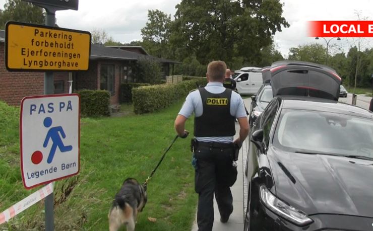 En hundepatrulje og politibiler foran et bosted