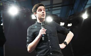 En komiker står med en mikrofon i hånden på en scene