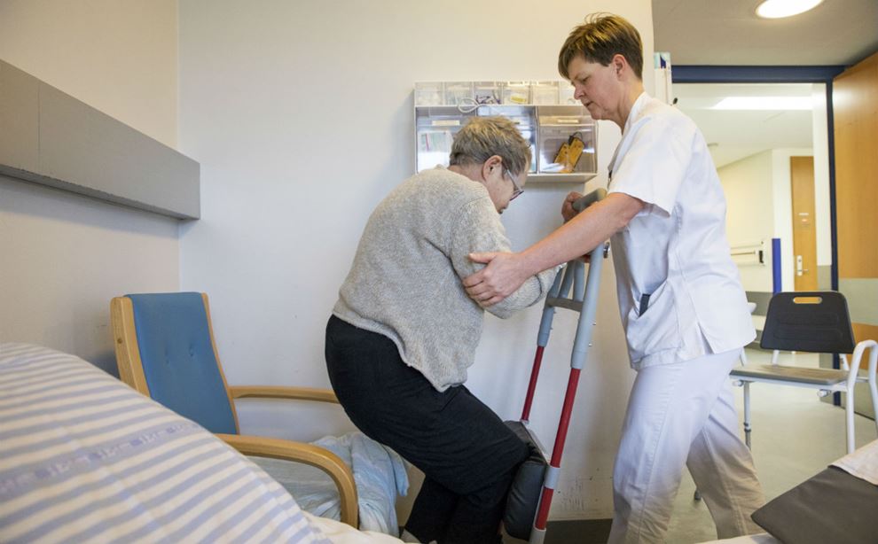 Sosu-assistent Birgitte Holmen hjælper patient med forflytning