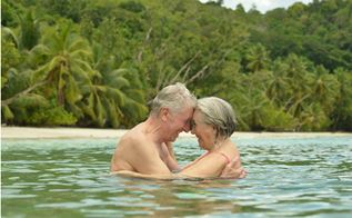 To ældre mennesker kærtegner hinanden ude i vandet ved strand