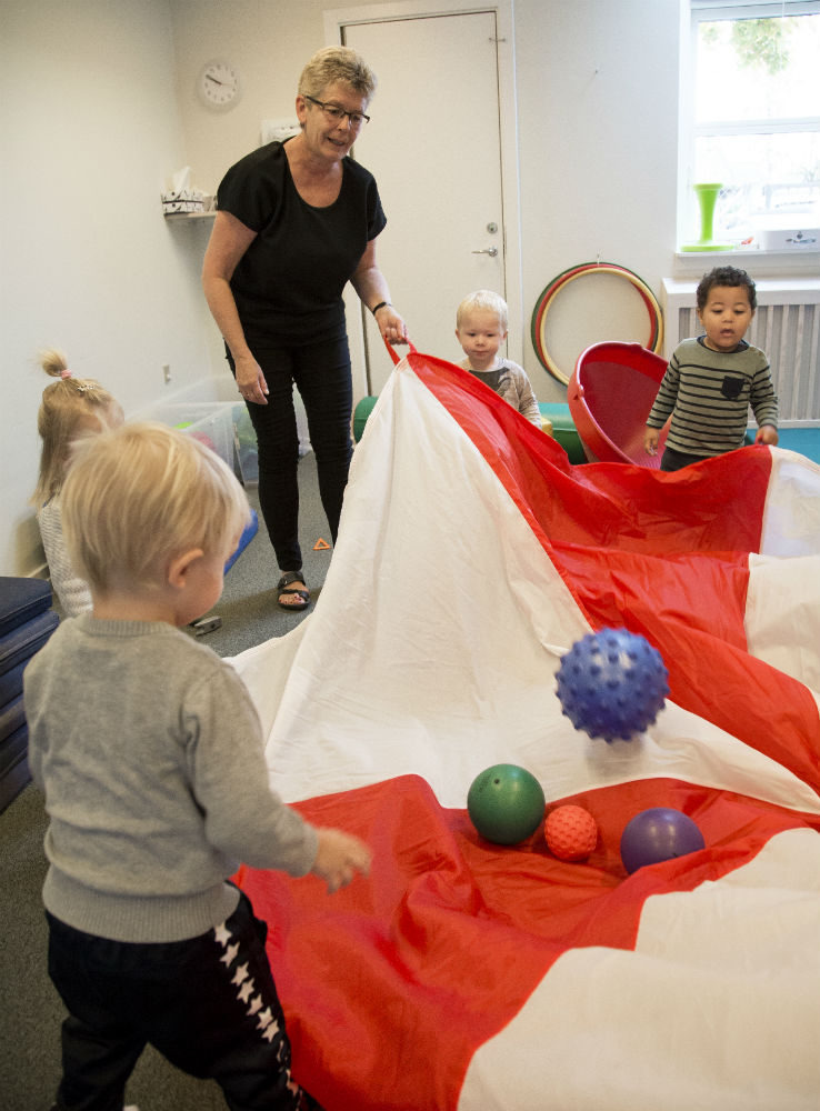 Dagplejer Pia Pihl og børn leger med faldskærm og bolde i Dagplejen Odense Syd