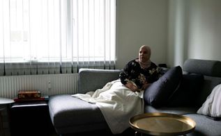 Kvinde sidder i sofa med tæppe over sig