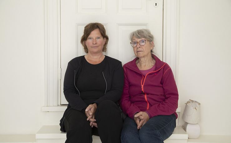 To kvinder sidder på trappe foran dør