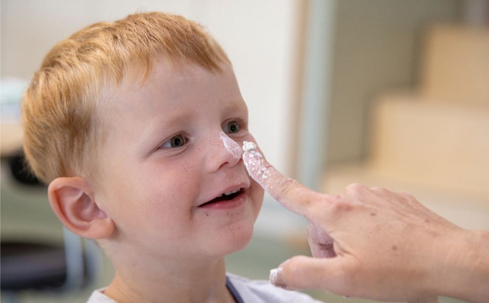 Dreng har mel på næsen, en finger peger på hans næse