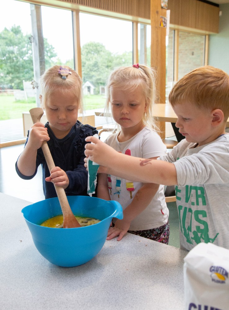 Tre børn rører i en skål