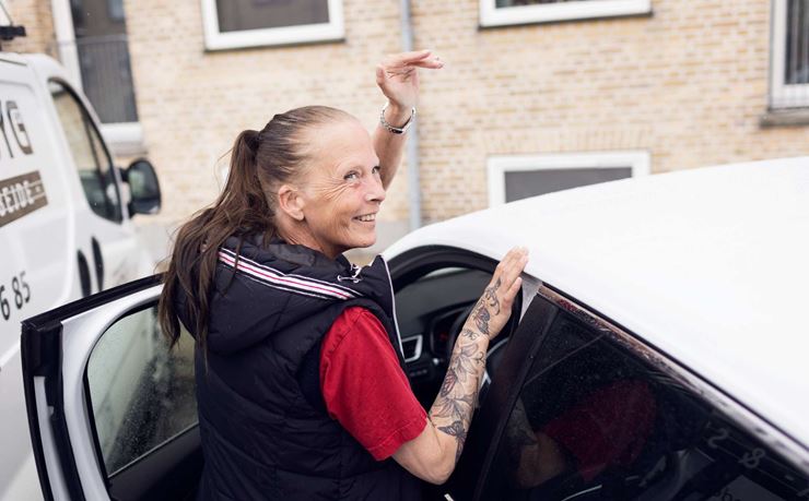 Annette Thomsen er på vej ind i sin bil i hjemmeplejen. Vinker til en borger.