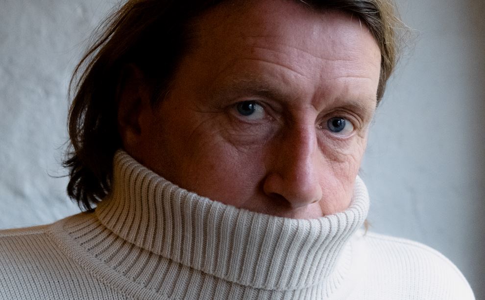 Anders Agger har trukket kraven på sin hvide sweater op over munden.