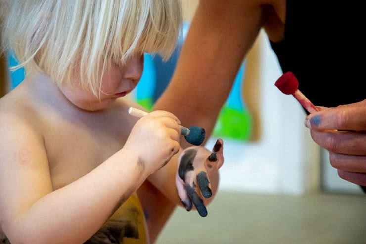 Et barn får hjælp til at male sine hænder